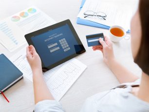 a woman sitting at a table with a tablet.